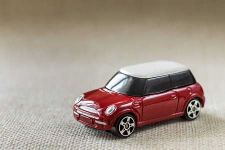 小亮红色金属简单儿童玩具车与深色窗户上的浅米色帆布复制空间背景。