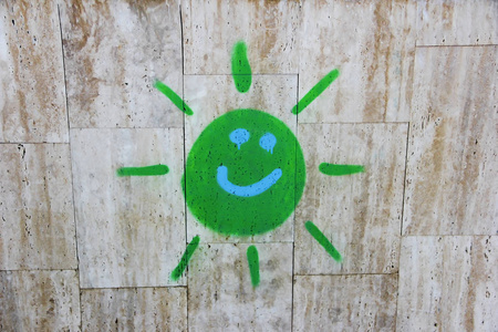 s drawing of green sun paints on a concrete gray wall