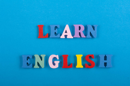 在蓝色背景上学习英语单词，由彩色ABC字母组成，木块木制字母，复制空间为广告文本。 学习英语
