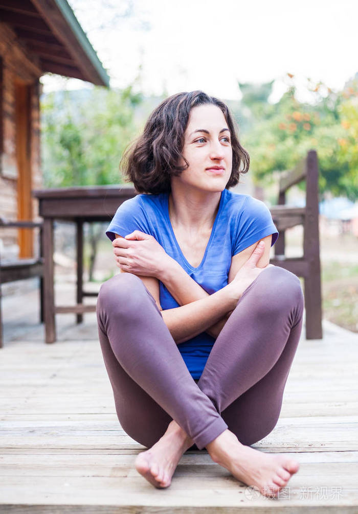 一个女人坐在一座旧木屋的门廊上在春天的一天赤脚女孩在房子附近休息