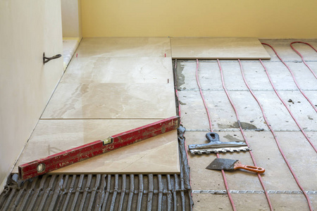 关闭水泥地板上瓷砖上的杠杆。 瓷砖安装工具和家居装修改造和施工舒适的现代家居理念。