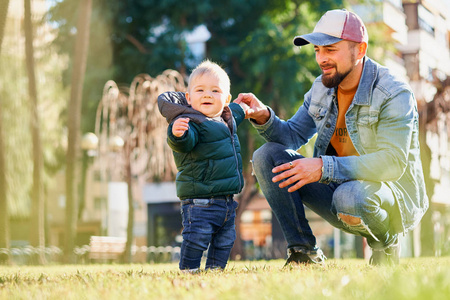 s hand when walking in the park on a sunny day. Father and son r