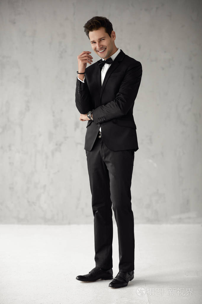 穿着黑色西装的英俊微笑男人看着摄像机