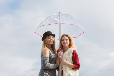 两个穿着时髦服装拿着透明雨伞的时髦女人在户外消磨时间