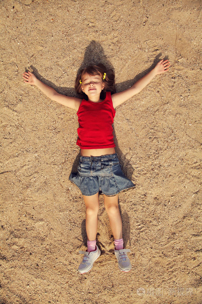 放松可爱的小女孩躺在沙滩上孩子在度假
