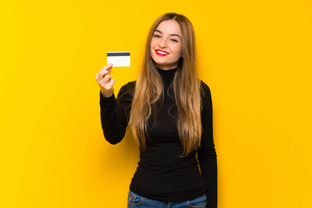 年轻漂亮的女人，黄背景，持有信用卡