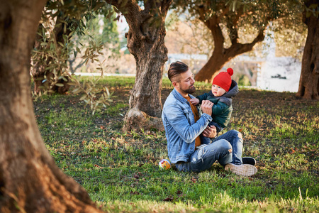 阳光明媚的一天，小胡子男和他可爱的小儿子在公园里玩。 一对父子。 家庭观念。