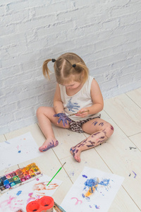 女孩，孩子用画笔和水彩画，画在一张纸和衣服上