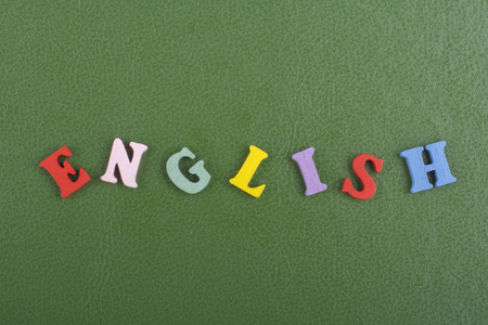绿色背景上的英文单词由五颜六色的ABC字母组成，木制字母，复制空间为广告文本。学习英语