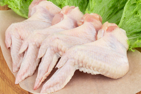 生鸡翅在砧板上用生菜。