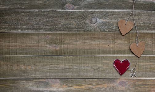 情人节。 2月14日概念。 两个木制的心用绳子绑着，一个单独的红色的心在棕色的老式木制背景上。 文本空间。