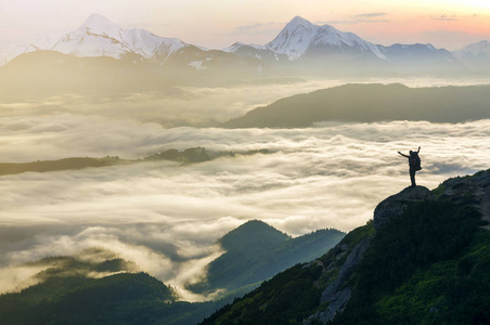 宽山全景。 游客的小轮廓与背包在岩石山坡上，举起手在山谷上覆盖着白色的蓬松云。 自然之美旅游之美和旅游理念