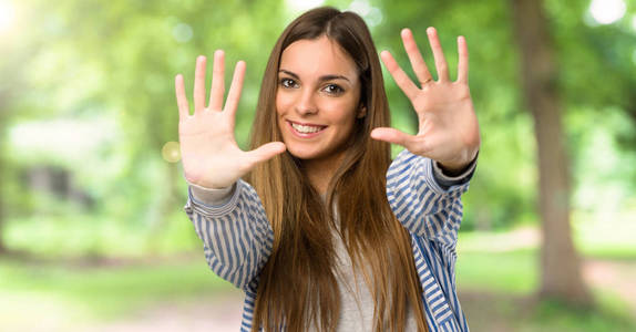 一个年轻女孩,穿着条纹衬衫,数到十,手指在户外照片