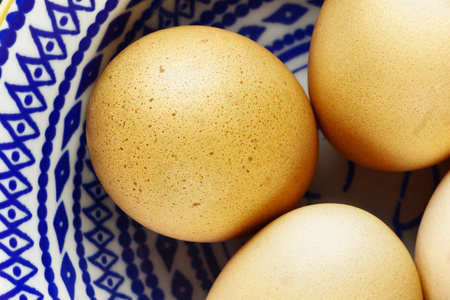 在白色的蓝色碗里看鸡蛋，美丽的光和蛋壳上的阴影