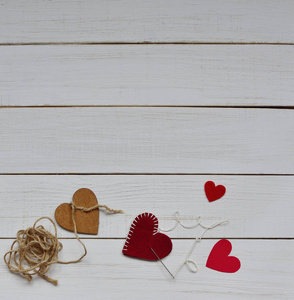情人节2月14日的概念。 用剪刀和红白装饰毡制作情人节礼物的过程，一颗心在白色复古的木制背景上未完成。 文本空间