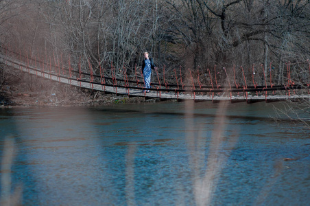 穿着长裙子的金发女孩在河对岸的老山雀桥上