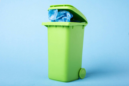 蓝色背景上的绿色垃圾箱。 聚乙烯。 文本空间。 回收利用。 生态概念。