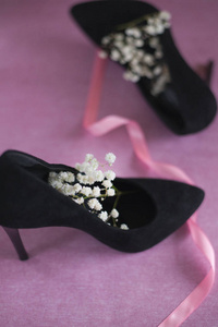 s black velvet shoes with white flowers on pink background, whit