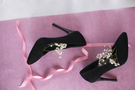 s black velvet shoes with white flowers on pink background