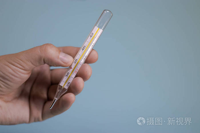 手拿温度计在蓝色背景上.