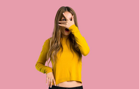 年轻女孩穿着黄色毛衣，带着惊讶和震惊的表情，在孤立的粉红色背景下