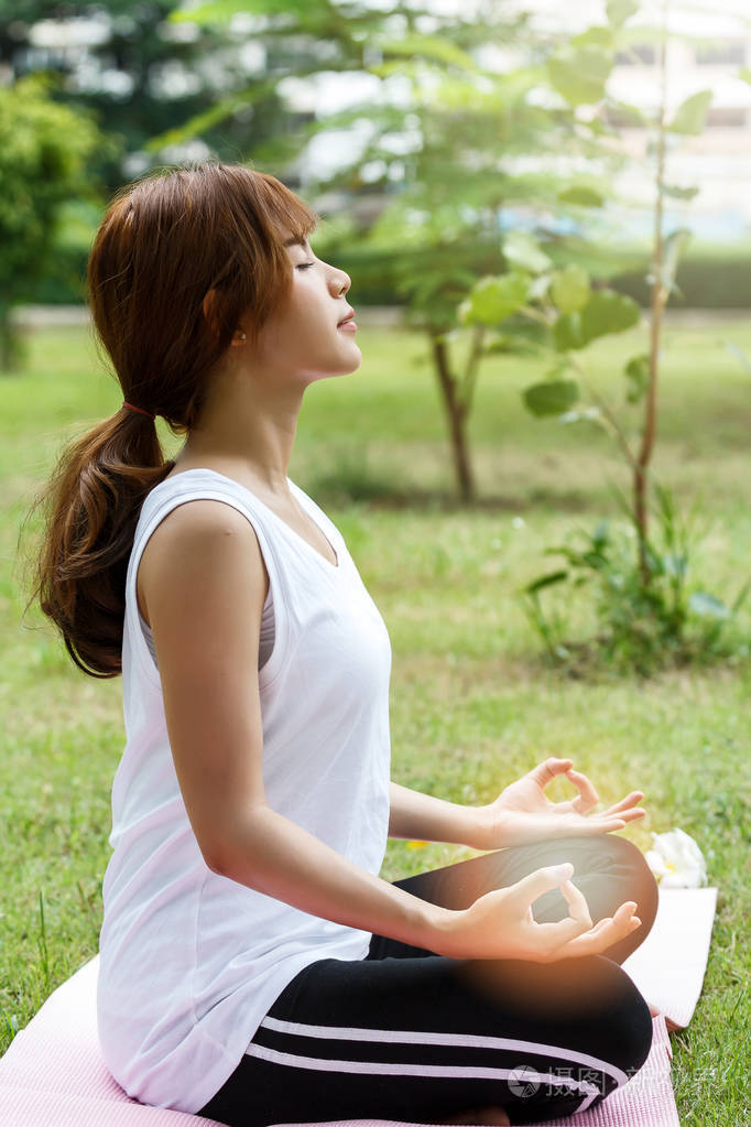 年轻的亚洲女人,穿着运动服,坐在瑜伽垫上的莲花姿势