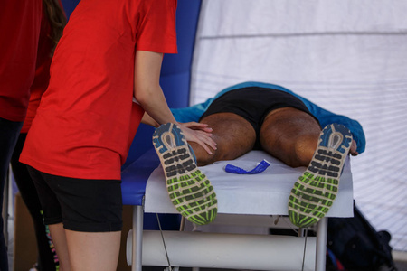 运动员躺在床上，在体育锻炼后进行腿部按摩。