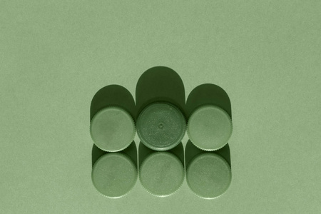 6个绿色塑料瓶盖在绿色背景上，圆形瓶盖成两排单色效果