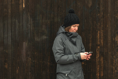 在寒冷的冬天下午，休闲女性在街上用手机发短信