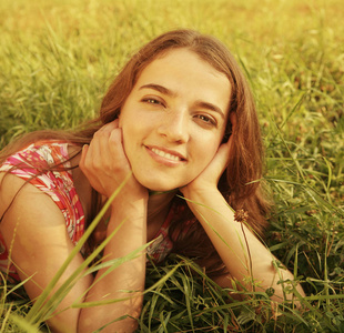 年轻美丽的女孩躺在草地