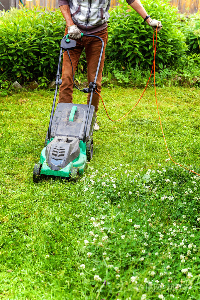 人在后院用割草机割草. 园艺乡村生活方式背景.