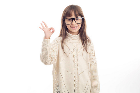 戴眼镜的快乐小女孩在白色背景上显示了一个OK标志隔离。