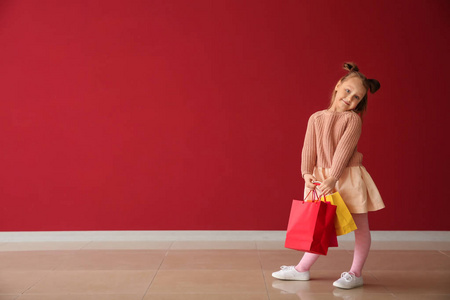 可爱的小女孩，靠近彩色墙的购物袋
