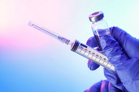 s hand with syringe and vaccine against flu on color background