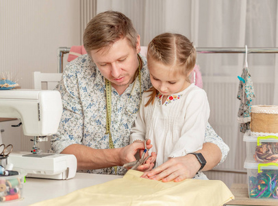 小女孩和她的爸爸在缝纫车间图片
