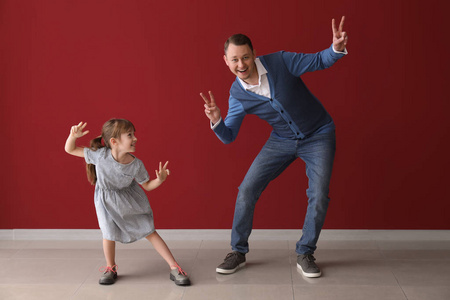 爸爸和他可爱的小女儿在彩墙旁跳舞