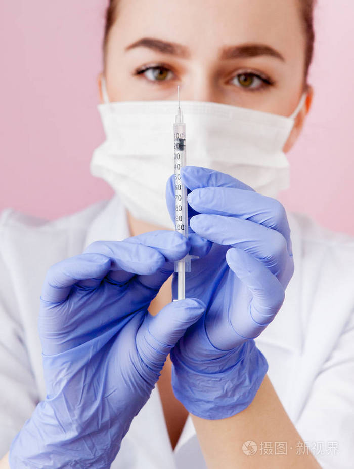 关闭护士拿着注射器在粉红色背景上注射.