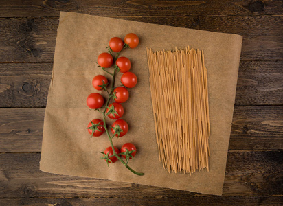意大利面和西红柿在黑暗的木制背景和复制空间。 上面的风景。 素食健康或烹饪概念