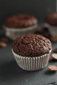 巧克力自制纸杯蛋糕松饼在黑色背景和巧克力滴在背景。 面包店风格。 深色食物照片垂直