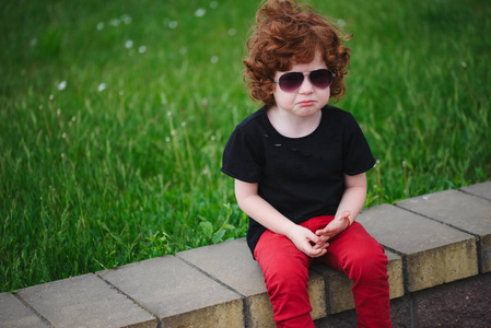 悲伤的红头发男孩在夏季公园