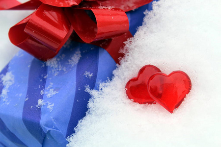 雪中两颗红色塑料心和礼物