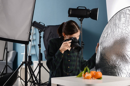 年轻女子在专业工作室拍摄新鲜橘子的照片