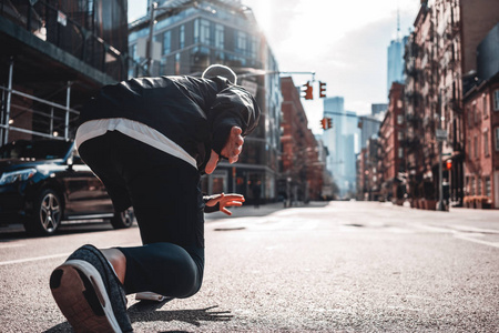 城市跑步者在城市街道上开始姿势的背面视图。 预先准备马拉松健康跑步概念