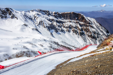 滑雪道在高尔基戈罗德冬季山滑雪胜地蓝天和雪岩风景背景。 索契俄罗斯高加索山脉