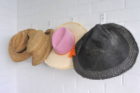 在一个夏天的家中，男人和女人的节日草帽挂在墙上