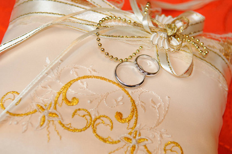 用丝带和刺绣装饰的垫子上的结婚戒指。 结婚纪念日。