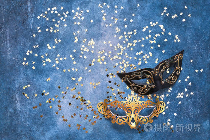 蓝色背景上的两个狂欢节面具和金色星星. 顶部视图复制空间.