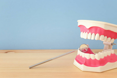 牙科护理工具用于牙科和塑料牙齿模型在诊所。 木制蓝色背景