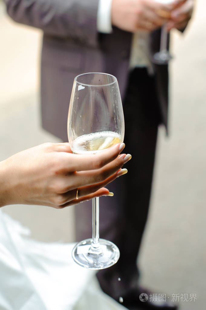 一只雌性手拿着一杯香槟手上有一滴香槟