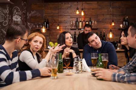 一群年轻的朋友坐在酒吧的桌子旁